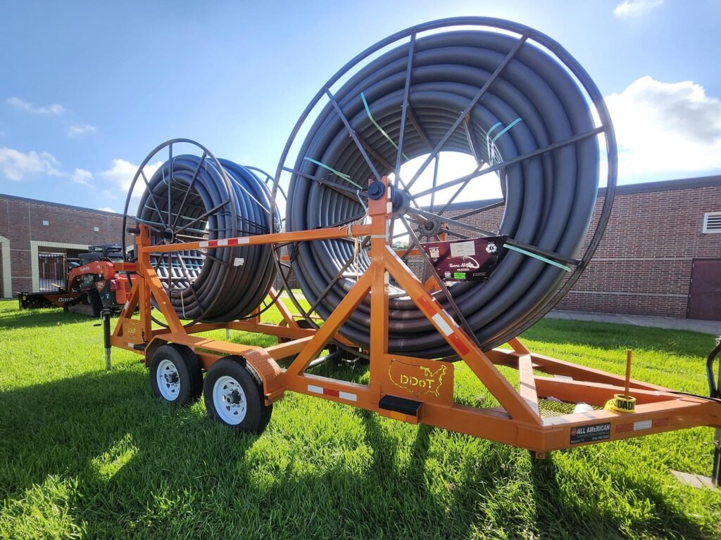 Dual-reel trailer loaded with coiled HDPE conduit for underground utility installation.
